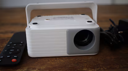 Elegimos los mejores proyectores portátiles para ver películas Proyector portátil en una mesa de madera.